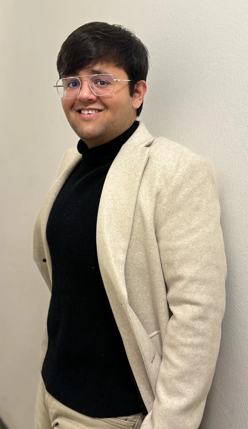 Kapil wearing a cream blazer and smiling