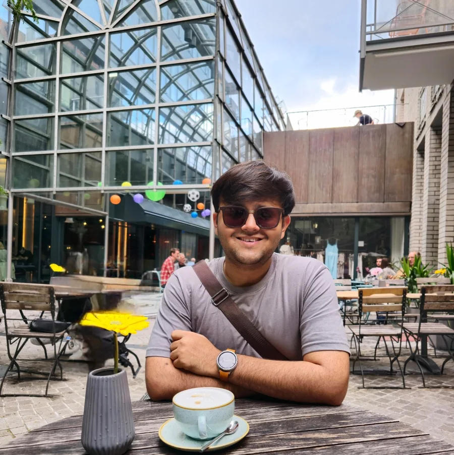 Kapil smiling over coffee at an outdoor café