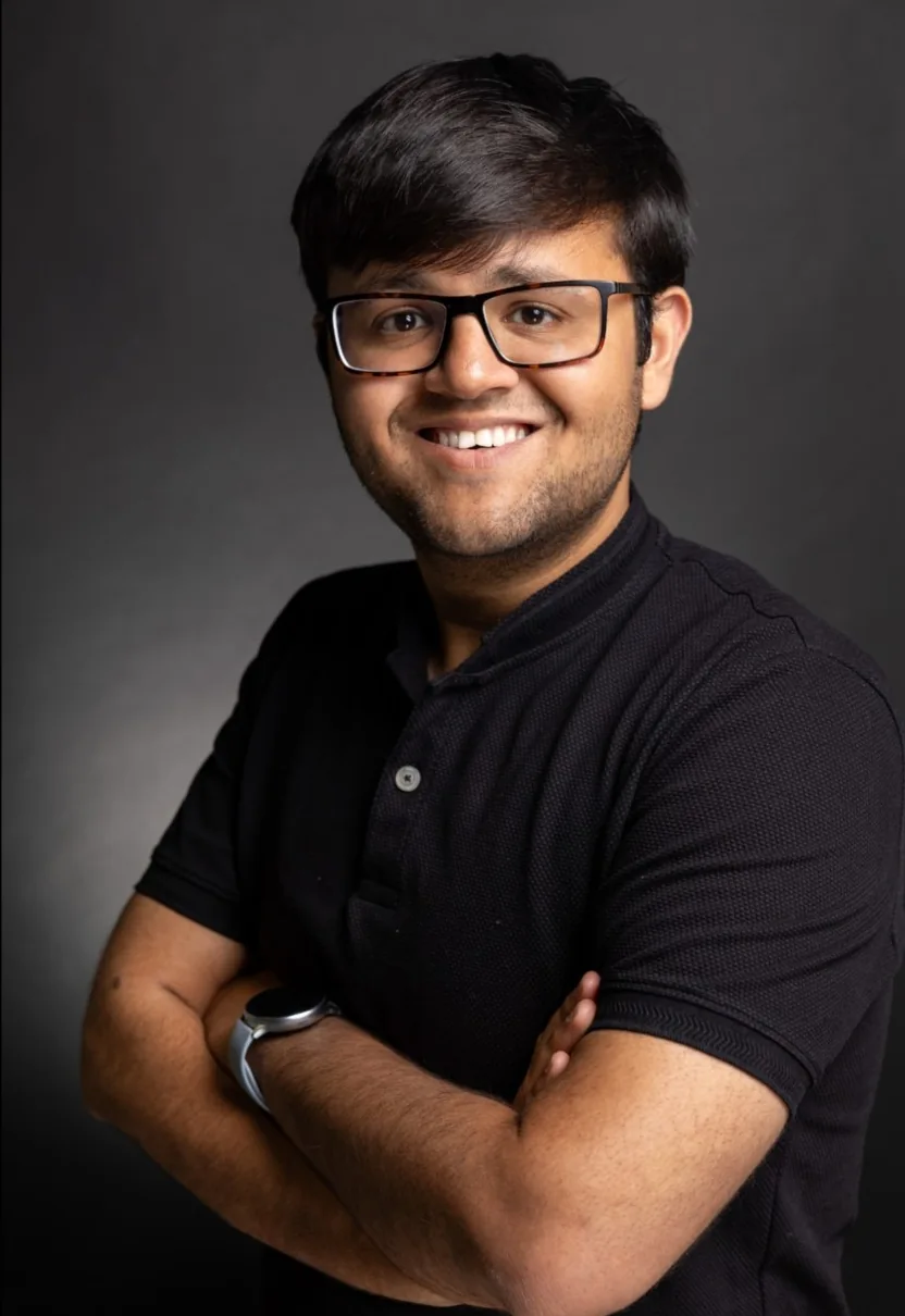 Kapil Mulchandani smiling in a black polo shirt against a studio background